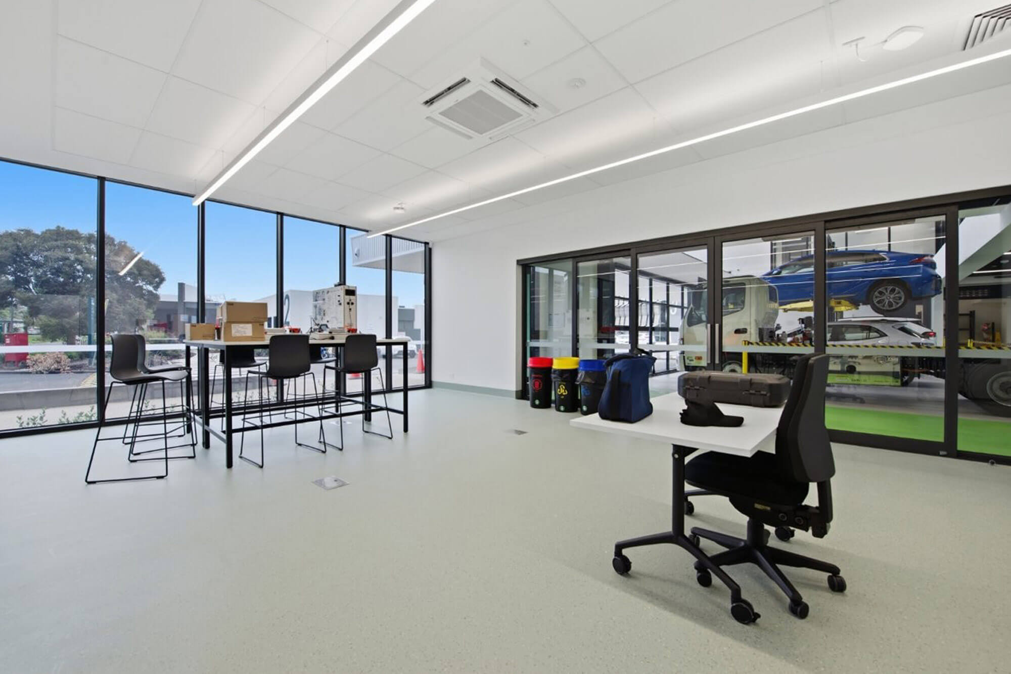 Inside the new TAFE Gippsland Clean Energy Centre training area, in a white room with polished concrete floor, and some contemporary desks and chairs.